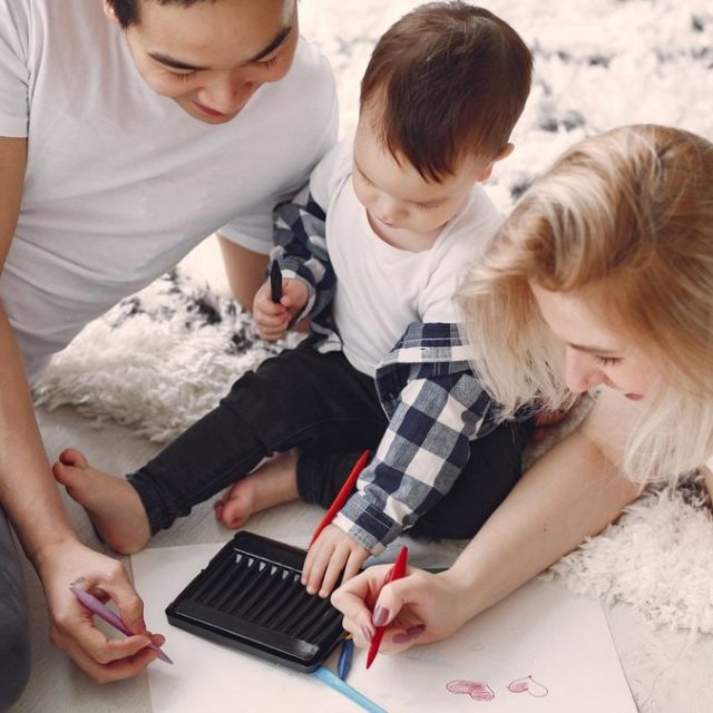 Parents and child enjoying drawing together on the floor, creating memories.